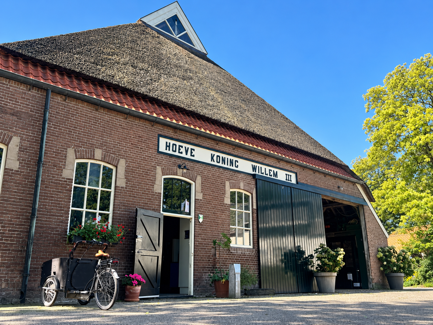 De voorgevel van Hoeve Koning Willem III met de open ingang en een fiets.