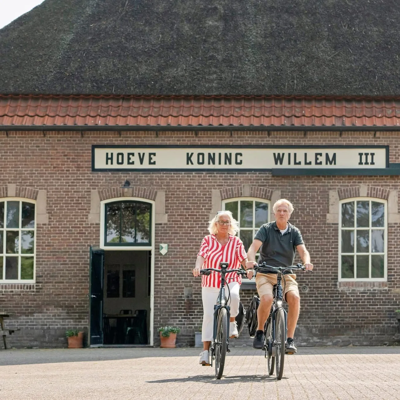 Twee fietsers voor de ingang van Hoeve Koning Willem III.